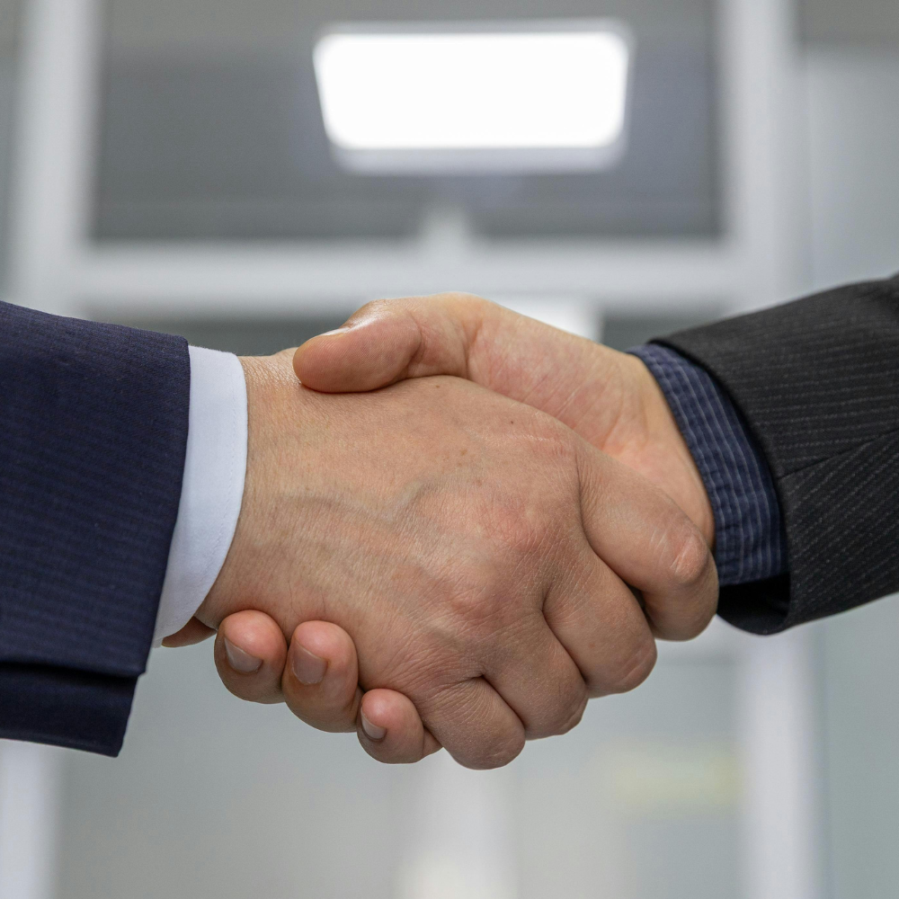 Two individuals shaking hands, symbolizing a strategic Business Correspondence partnership enabled by Twinline.org for financial institutions collaborating on last-mile service delivery