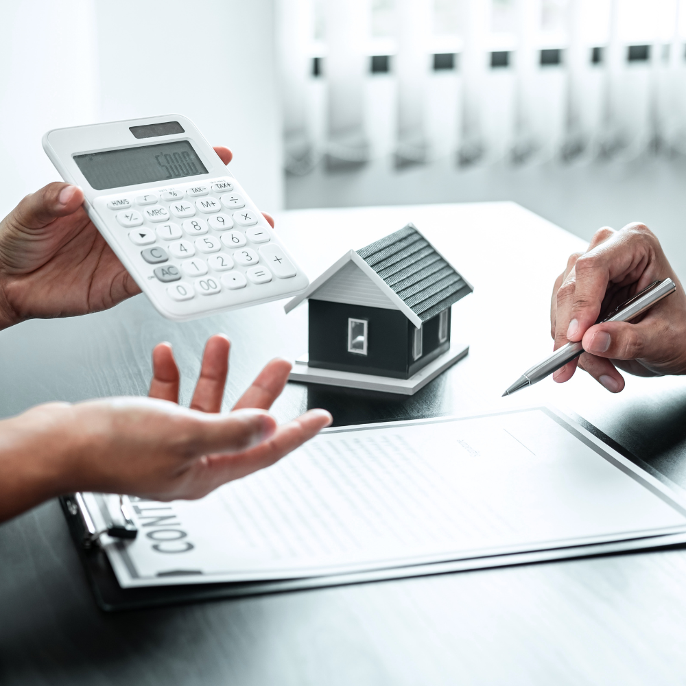 A pen poised over a loan application form for Loan Against Property, with a calculator and a model house nearby, representing property-backed lending automated by NBFCs and MFIs using Twinline.org's software.