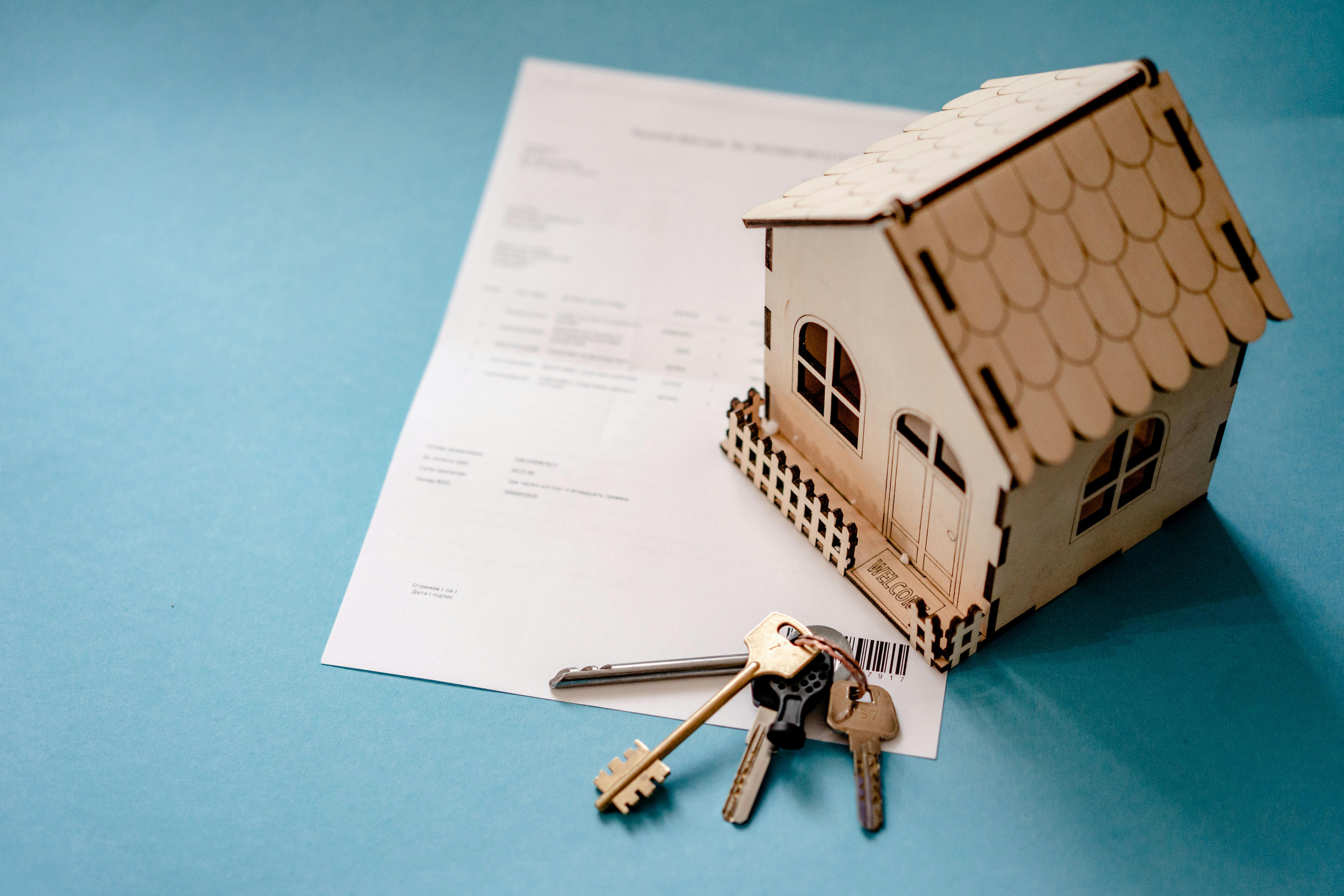 A signed loan document placed beside a house model and a set of keys, representing successful disbursement of a property-backed loan through NBFCs and MFIs using Twinline.org's lending software.